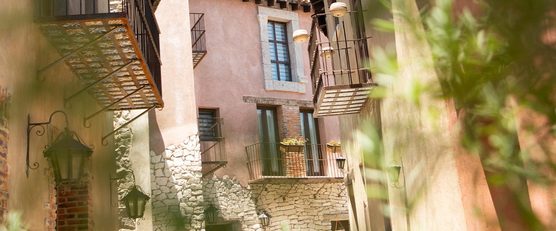 Calle empedrada de Val'Quirico con balcones de herrería y vegetación